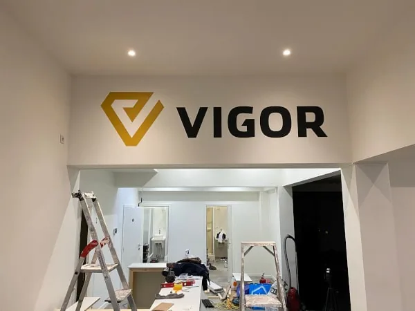 Logomuurl met doosletters in een pand in opbouw, met een ladder ervoor